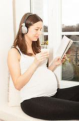 Image showing pregnant women drink a glass of milk and listening to music