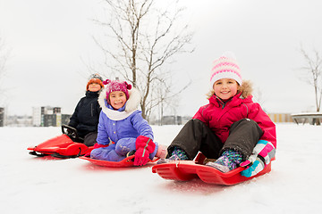 Image showing happy little kids sliding on sleds in winter