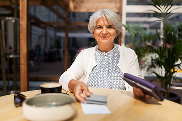 Image showing senior woman with credit card paying bill at cafe