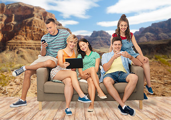 Image showing friends with tablet pc and smartphones sit on sofa