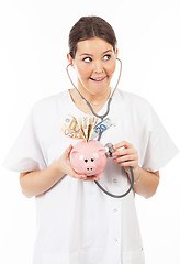 Image showing happy woman doctor with piggy bank full of money