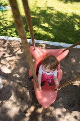 Image showing little girl swinging  on a playground