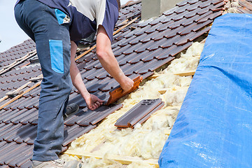 Image showing a roofer laying tile on the roof