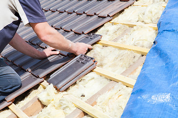 Image showing a roofer laying tile on the roof