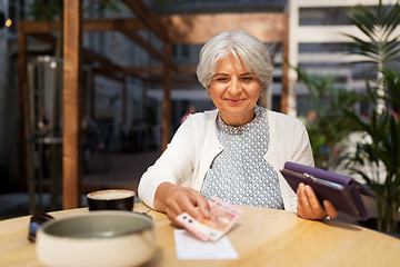 Image showing senior woman with money paying bill at cafe