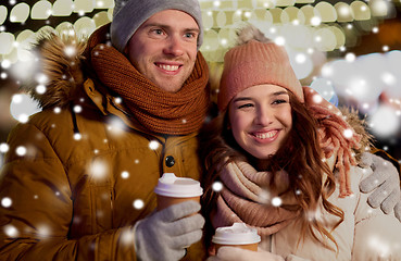 Image showing happy couple with coffee over christmas lights