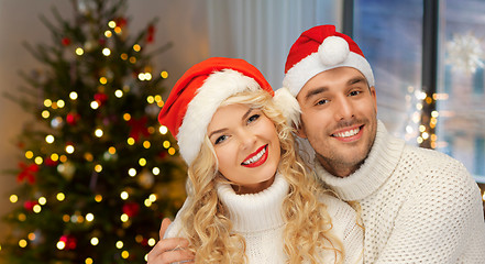 Image showing couple in santa hats over christmas tree lights