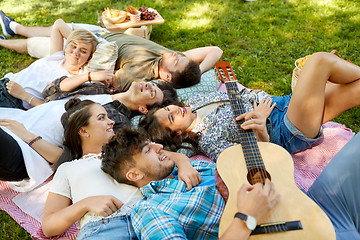 Image showing friends playing guitar and chilling at summer park