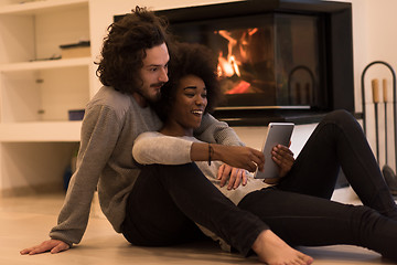 Image showing multiethnic couple using tablet computer on the floor