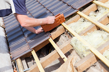 Image showing a roofer laying tile on the roof