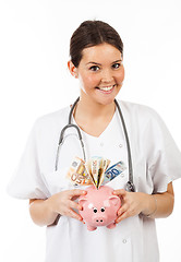 Image showing happy woman doctor with piggy bank full of money