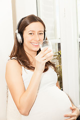 Image showing pregnant women drink a glass of milk and listening to music