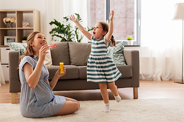 Image showing pregnant mother and daughter blowing soap bubbles