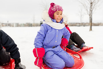 Image showing little girl on snow saucer sled in winter