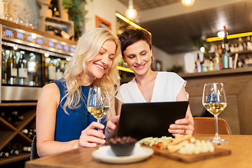 Image showing women with tablet pc at wine bar or restaurant