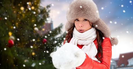 Image showing woman blowing to snow over christmas tree