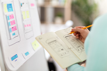 Image showing ui designer with user interface sketch in notebook