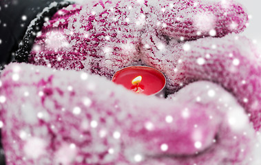 Image showing close up of hands in winter mittens holding candle