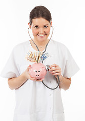 Image showing happy woman doctor with piggy bank full of money