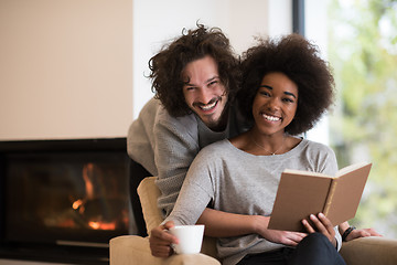 Image showing multiethnic couple hugging in front of fireplace