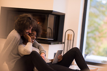 Image showing multiethnic couple using tablet computer on the floor