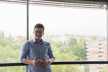 Image showing Businessman Standing In A Modern Building Near The Window With P