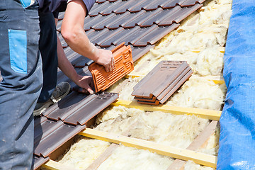 Image showing a roofer laying tile on the roof