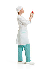 Image showing beautiful young woman doctor in medical robe holding syringe in hand.