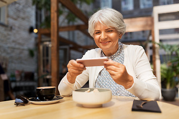 Image showing senior woman photographing food at street cafe