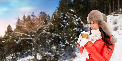 Image showing woman in fur hat with coffee over winter forest