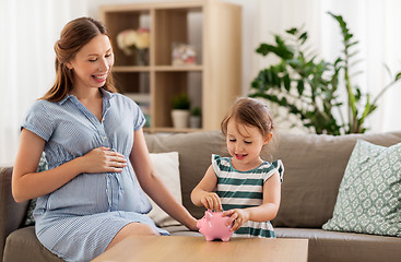 Image showing pregnant mother and daughter with piggy bank