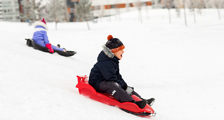 Image showing happy kids sliding on sleds down hill in winter