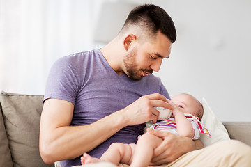 Image showing father feeding baby daughter from bottle at home