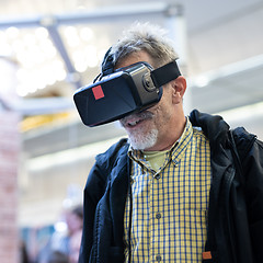 Image showing Senior man wearing virtual reality goggles watching virtual reality presentation.