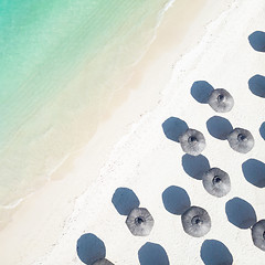 Image showing Aerial view of amazing tropical white sandy beach with palm leaves umbrellas and turquoise sea.