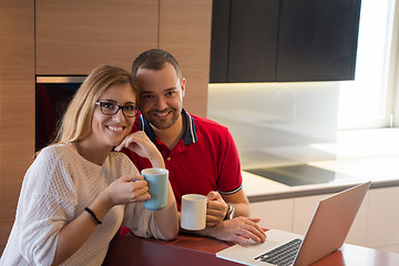 Image showing couple drinking coffee and using laptop at home