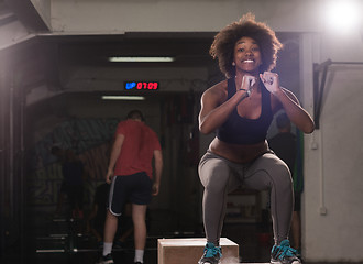 Image showing black female athlete is performing box jumps at gym