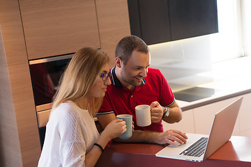 Image showing couple drinking coffee and using laptop at home