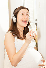 Image showing happy pregnant woman singing and listening to music