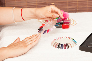 Image showing Hands of a woman who chooses the color of her nail polish