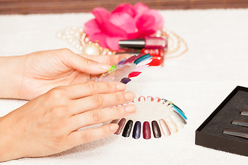 Image showing Hands of a woman who chooses the color of her nail polish