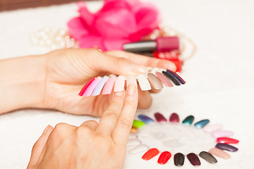 Image showing Hands of a woman who chooses the color of her nail polish