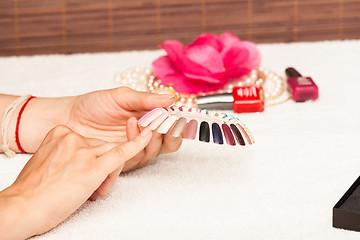 Image showing Hands of a woman who chooses the color of her nail polish