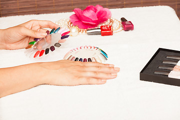 Image showing Hands of a woman who chooses the color of her nail polish