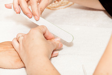 Image showing The beautician polish the client\'s nails before putting nail polish