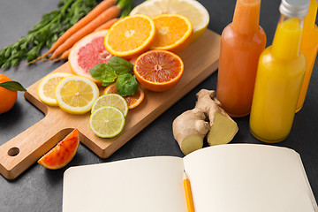 Image showing close up of fruits, juices and notebook on table