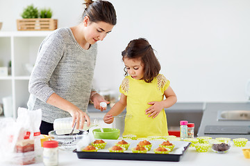 Image showing happy mother and daughter baking muffins at home