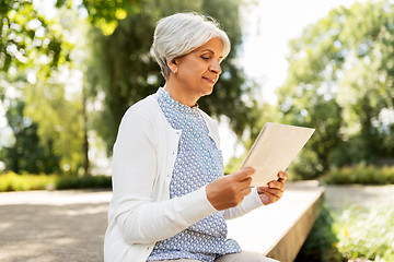 Image showing senior woman reading newspaper at summer park