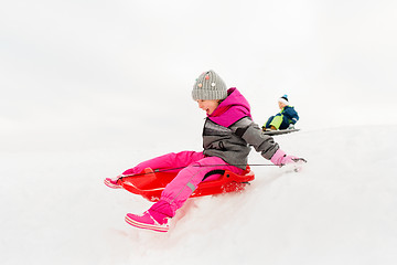 Image showing happy little girl sliding down on sled in winter