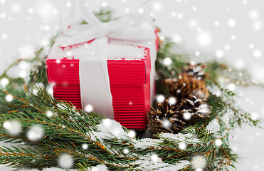 Image showing christmas gift and fir wreath with cones on snow